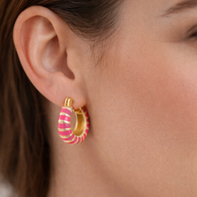 Load image into Gallery viewer, Woman wearing gold hoop earrings that are painted with two shades of pink enamel stripes