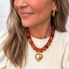 Load image into Gallery viewer, Chunky honey brown beaded necklace is perfect to add a pop of color to your fall outfit. The gold heart charm is removable allowing 2 different looks