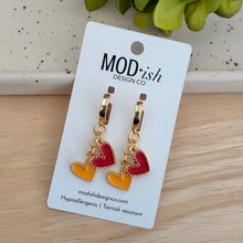 Load image into Gallery viewer, The only pair of earrings you'll reach for on Chiefs game days! 18k gold plated huggie hoops with a red enamel heart and a yellow enamel heart charm.