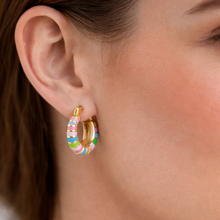 Load image into Gallery viewer, Woman wearing gold hoop earrings that are painted with colorful enamel stripes
