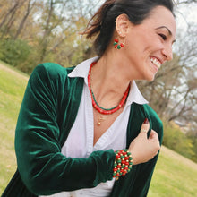 Load image into Gallery viewer, Woman wearing a green velvet cardigan over a white shirt with jewelry outdoors.
