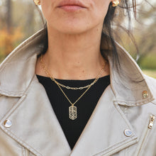 Load image into Gallery viewer, Person wearing a beige jacket with a gold necklace featuring a geometric pendant.
