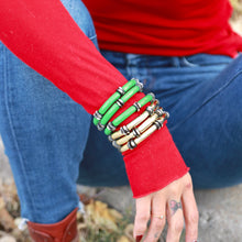 Load image into Gallery viewer, Person wearing a red long-sleeve shirt, blue jeans, and multiple bracelets on a natural background.
