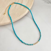 Load image into Gallery viewer, Turquoise beaded necklace with gold accents on a light wooden surface
