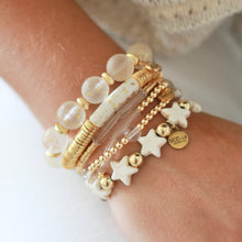 Load image into Gallery viewer, Stack of gold and white beaded bracelets on a wrist against a neutral background

